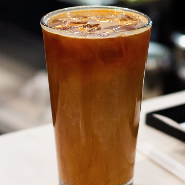 Close-up of a tall glass of iced coffee with a rich, dark brown color and ice cubes.