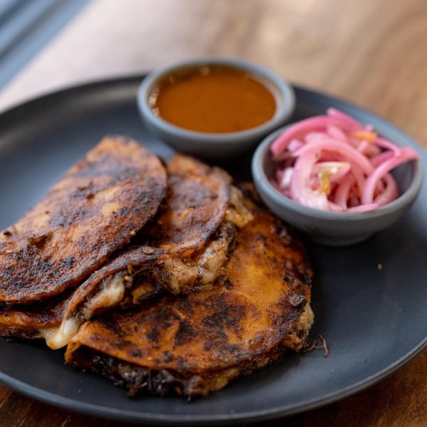 Crispy La Finca quesadillas with melted cheese, served with dipping sauce and pickled red onions.