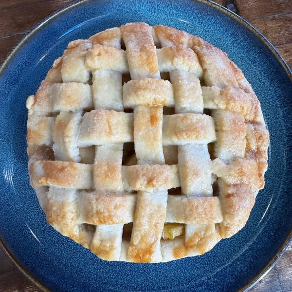 A golden-brown apple pie with a lattice crust, sprinkled with sugar, on a blue plate.